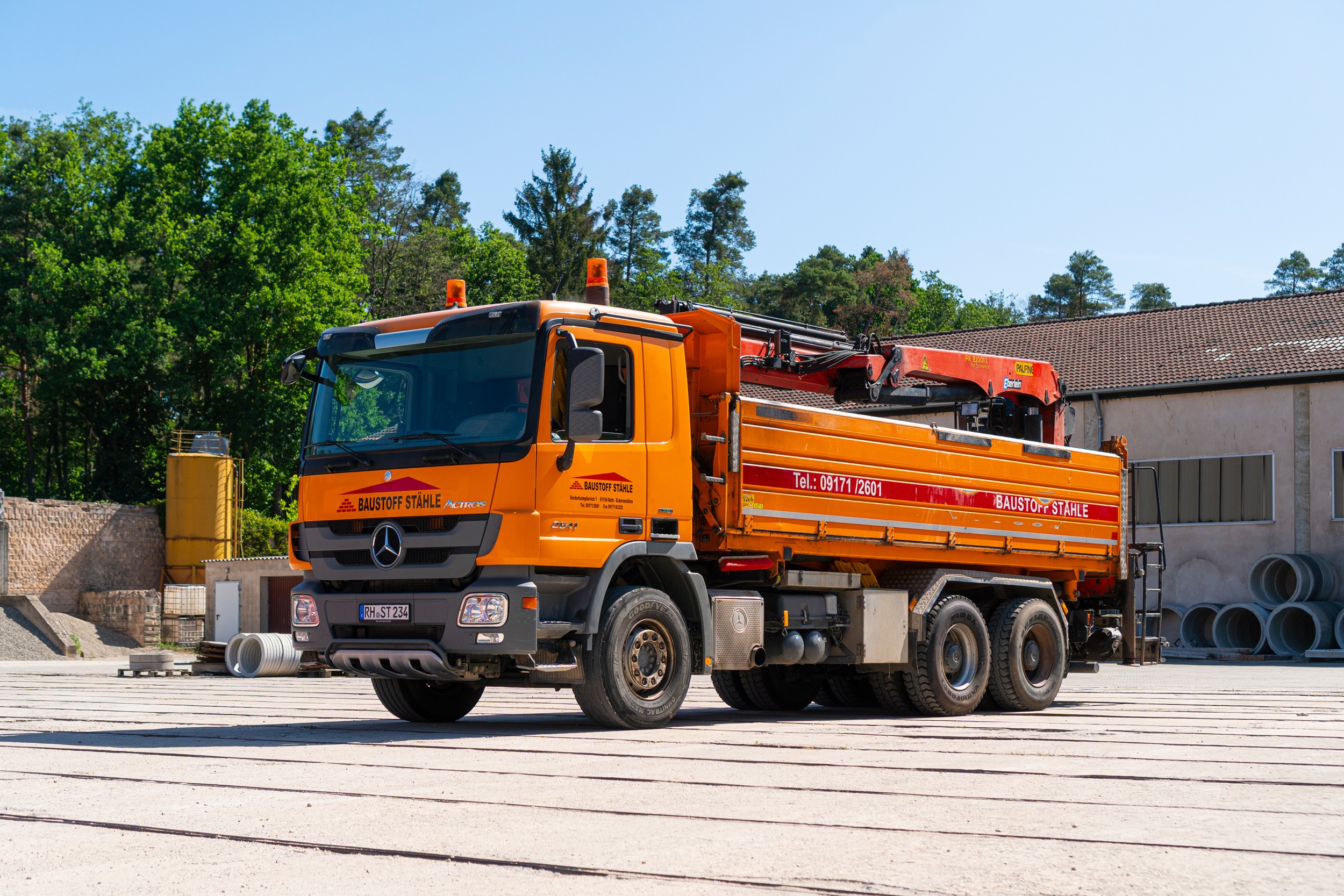 Dreiseitkipper in Komplettansicht und orangener Farbe auf dem Firmengelände