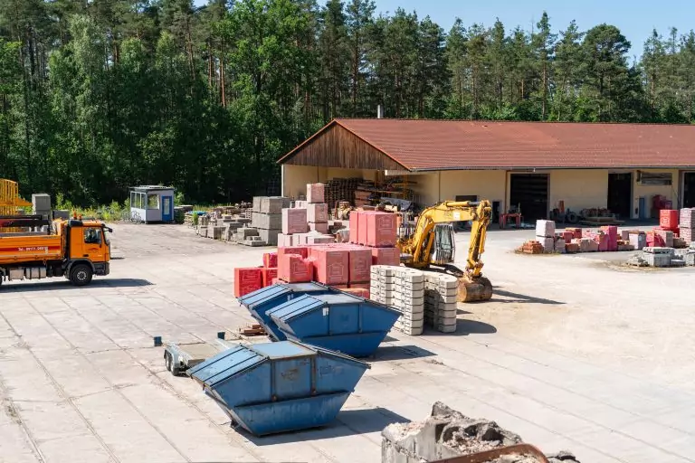 Luftbild auf den Hof der Firma mit orangenem LKW und Containern und Einarm Bagger
